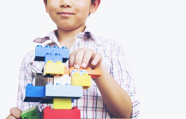 Foto menino bonito brincando com brinquedos em fundo branco