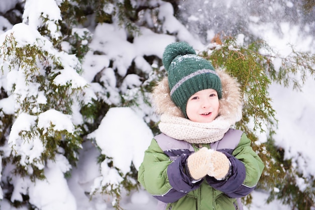 Menino bonito brincar com neve no parque. Espírito de natal