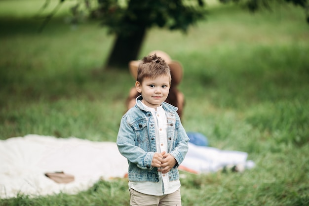 Menino bonito, caucasiano, com roupas elegantes, passeando