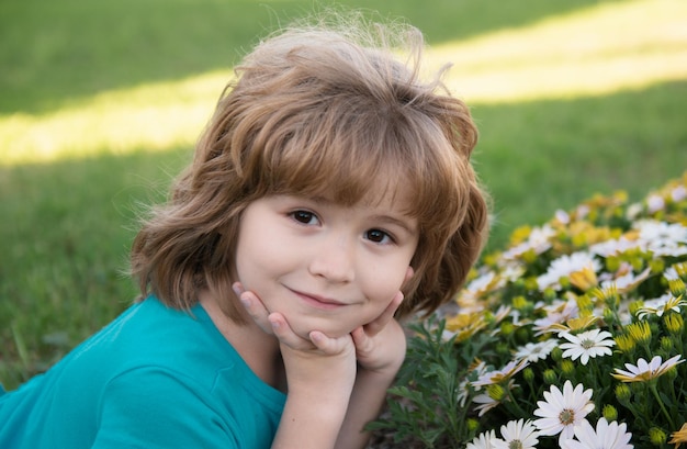 Menino bonito colhendo flores no jardim de verão florescente rosto de criança de primavera criança feliz