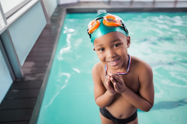 Menino bonito com sua medalha na piscina