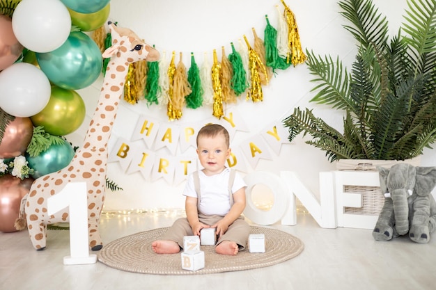 Menino bonito comemora seu primeiro aniversário no fundo de balões coloridos brilhantes e adereços festivos o primeiro feriado infantil