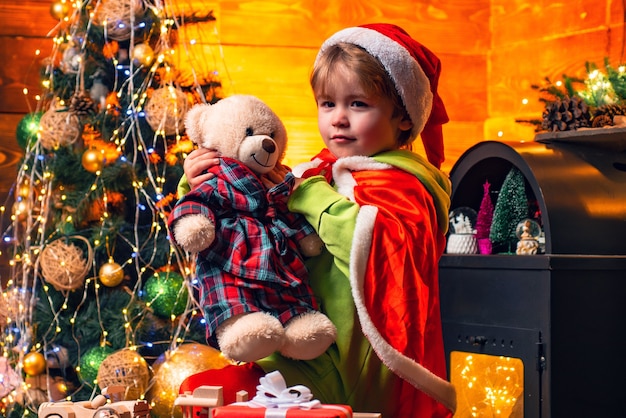 Menino bonito criança brincar perto de árvore de Natal. Presentes e surpresas. Feliz Natal e Feliz Ano Novo. Criança gosta de férias de inverno em casa. Casa cheia de alegria e amor. Natal do dia da família.