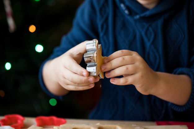 Menino bonito criança fazer biscoitos de gengibre de Natal na cozinha de ano novo.