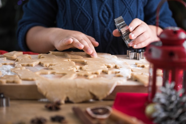 Menino bonito criança fazer biscoitos de gengibre de Natal na cozinha de ano novo.