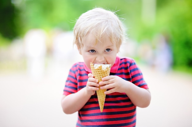 Menino bonito da criança comendo sorvete de baunilha