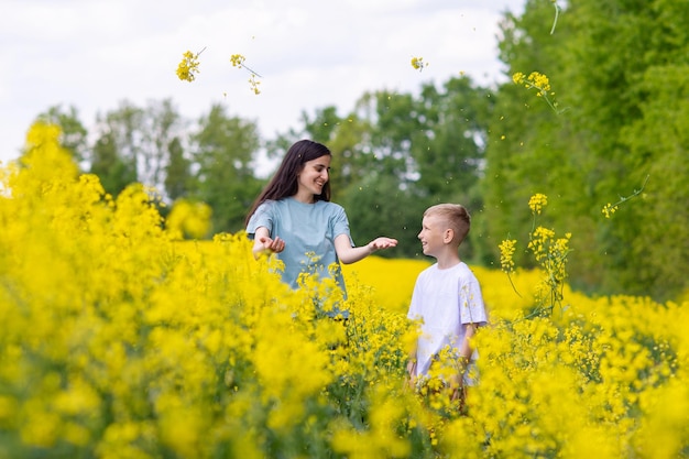 Menino bonito e irmã vomitam flores amarelas no campo