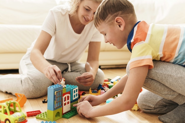 Menino bonito e sua mãe feliz brincando juntos em casa