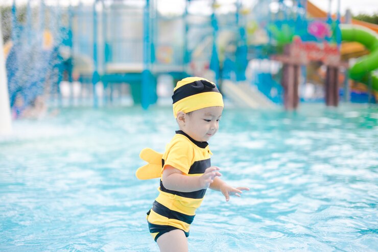 Menino bonito em maiô amarelo jogar na bela piscina azul