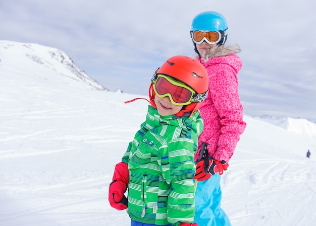 Menino bonito esquiador feliz com a irmã em uma estância de esqui de inverno.