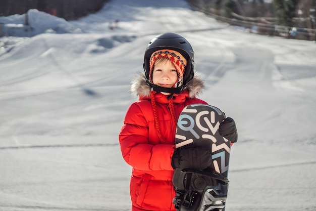 Menino bonito está pronto para atividades de snowboard para crianças no esporte de inverno infantil de inverno