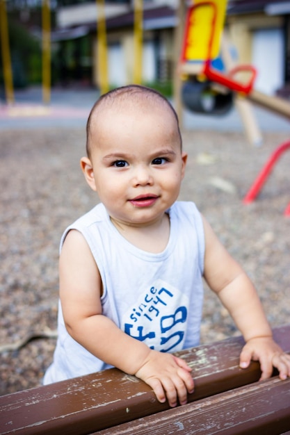 Menino bonito, feliz e sorridente, brincando com um carrinho de brinquedo colorido no parquinho infantil ao ar livre