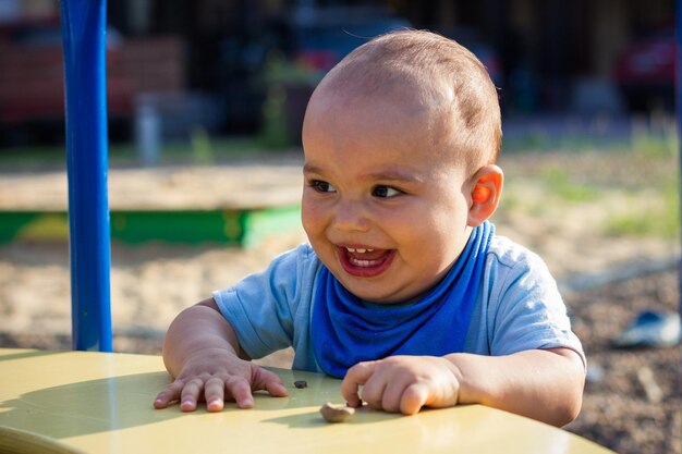 Menino bonito, feliz e sorridente, caminhando no parquinho infantil ao ar livre