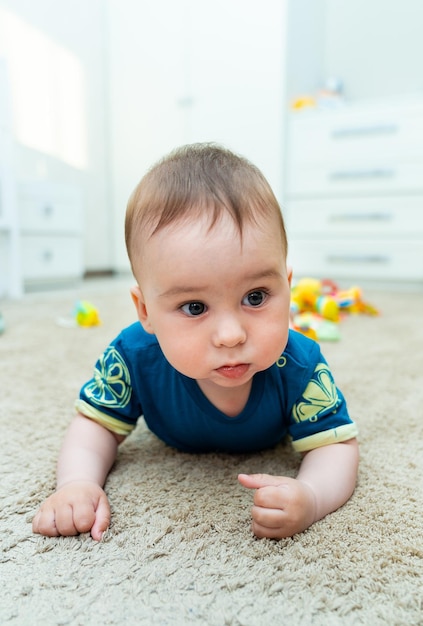 Menino bonito feliz jogando brinquedos em seu quarto de criança Lindo bebê rasteja pela casa
