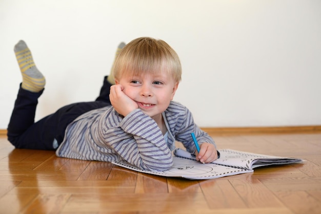 menino bonito lê o livro no chão em casa