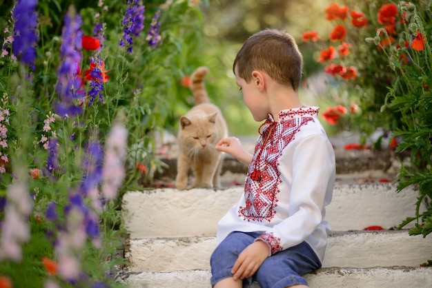 Menino bonito morena 5-6 anos de idade em um traje tradicional em um campo de papoulas no verão