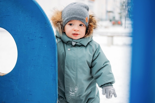 Menino bonito no chapéu de malha quente e cinza quente na rua de inverno