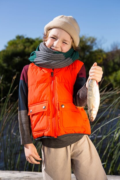 Menino bonito segurando peixe