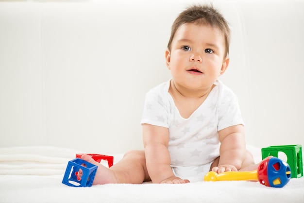 Menino bonito sentado em casa com brinquedos