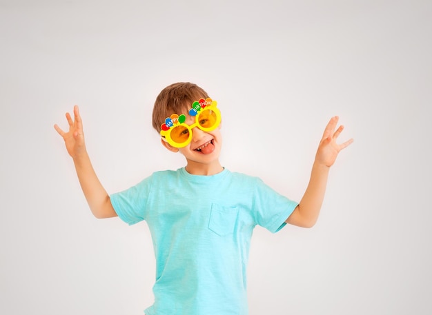 Menino bonito usando óculos de festa com texto de feliz aniversário. menino de óculos amarelos