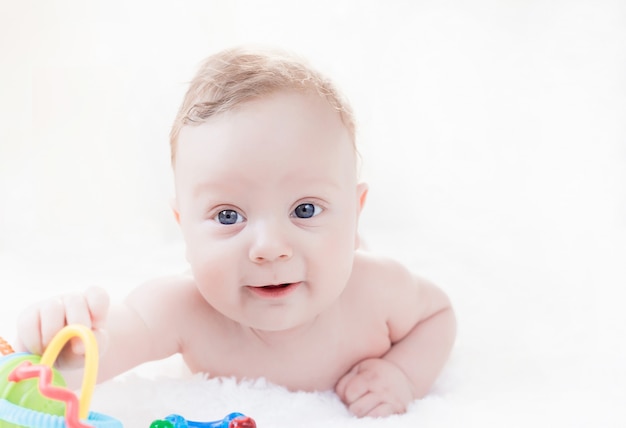 Menino branco de quatro meses com olhos azuis, deitado de bruços em um branco