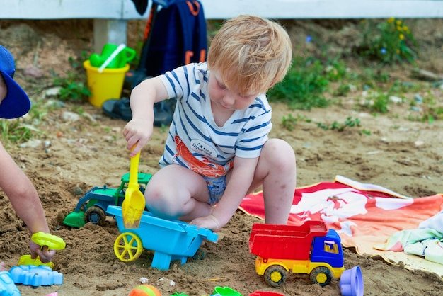 Foto menino brinca na areia com brinquedos de plástico