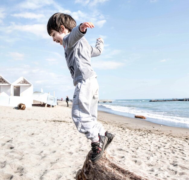 Foto menino brincalhão a brincar com areia na praia.