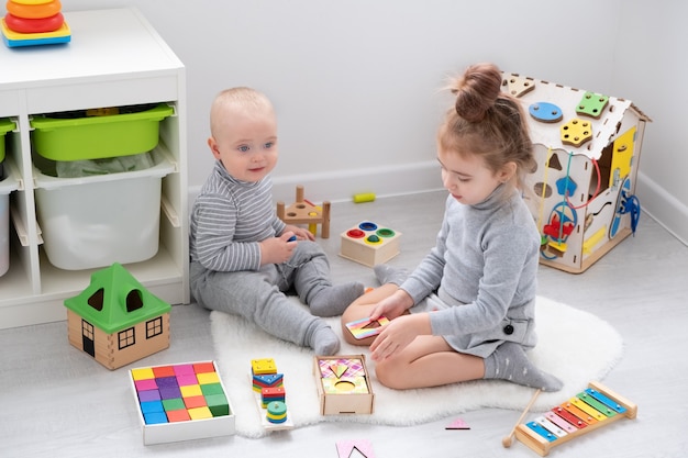 Menino brincando com a irmã mais velha com brinquedos de madeira