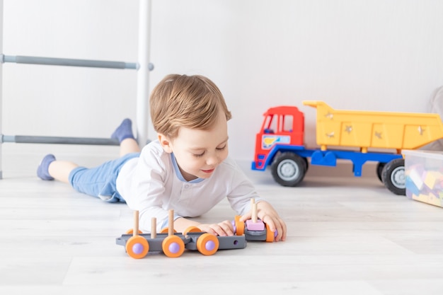 Menino brincando com brinquedos de madeira em casa no chão.