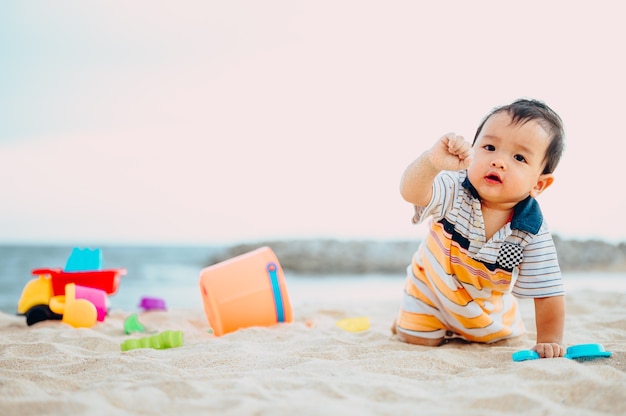 Menino brincando com brinquedos de praia com sua mãe na praia tropical.