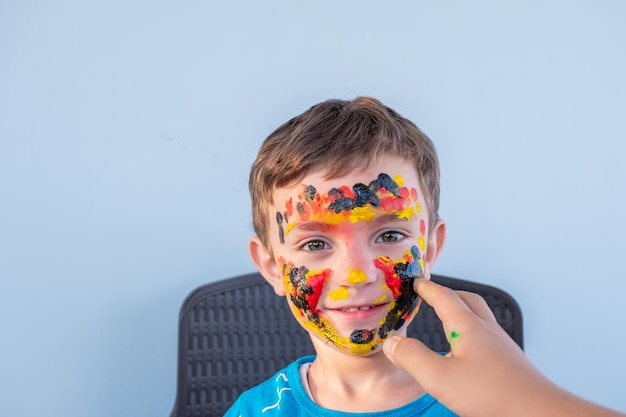 Menino brincando com cores usando as mãos e o rosto