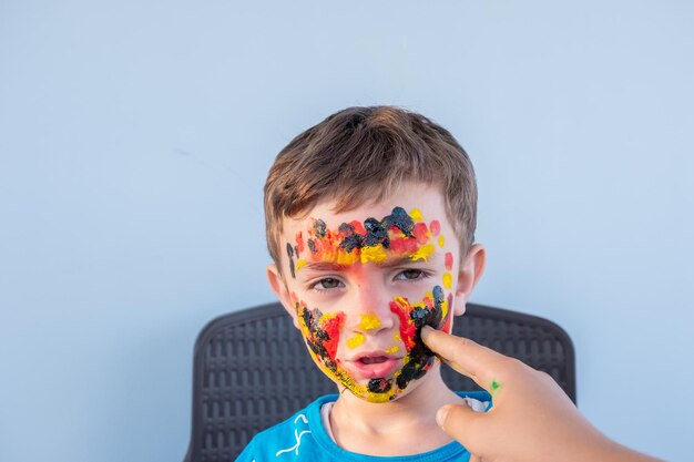 Menino brincando com cores usando as mãos e o rosto