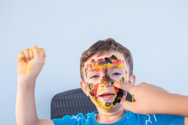 Menino brincando com cores usando as mãos e o rosto