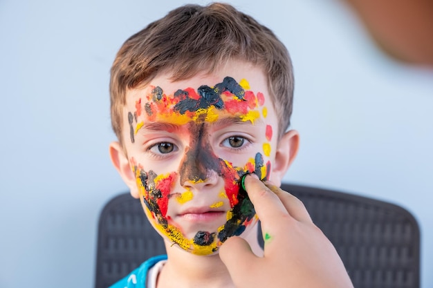 Menino brincando com cores usando as mãos e o rosto