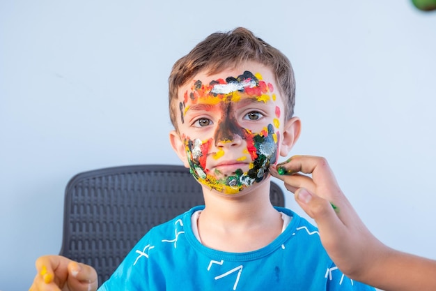 Menino brincando com cores usando as mãos e o rosto