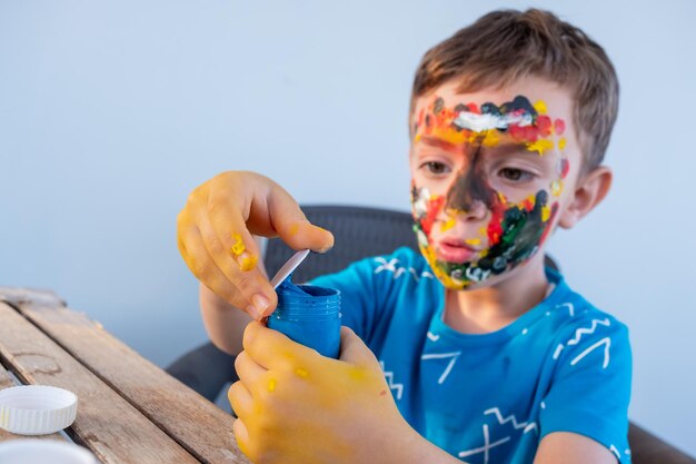 Menino brincando com cores usando as mãos e o rosto