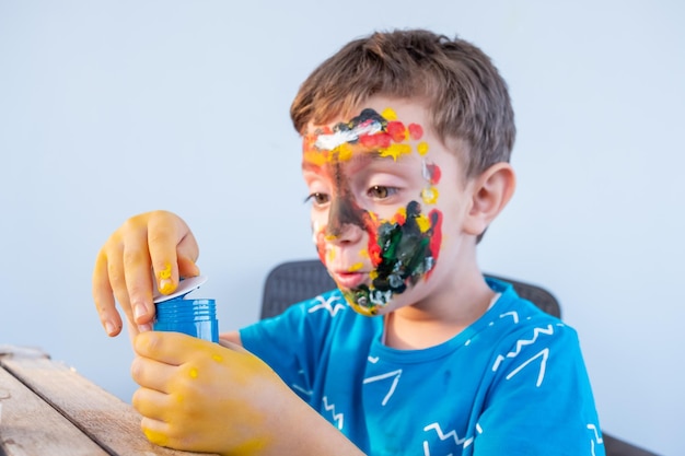 Menino brincando com cores usando as mãos e o rosto