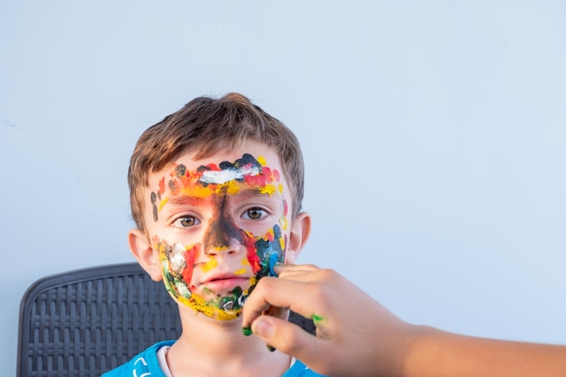 Menino brincando com cores usando as mãos e o rosto