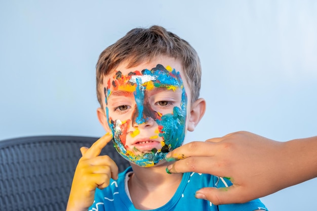 Menino brincando com cores usando as mãos e o rosto