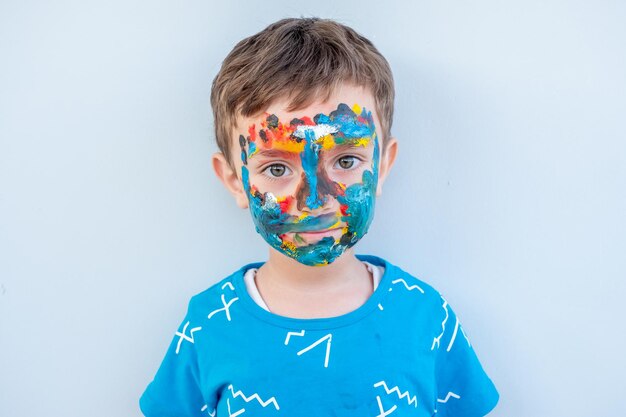 Foto menino brincando com cores usando as mãos e o rosto