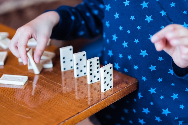 Menino brincando com dominó de perto Construa uma cerca de dominó de perto