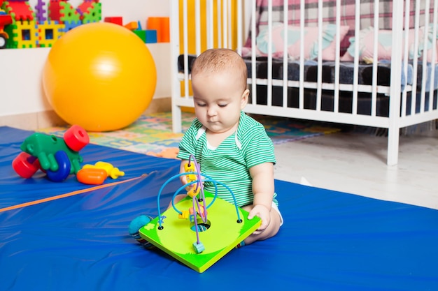 Menino brincando com labirinto para habilidades motoras finas no berçário