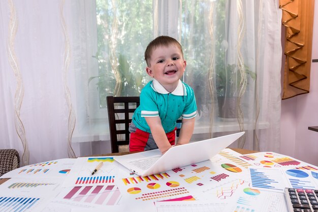 Menino brincando com o laptop no local de trabalho do analista