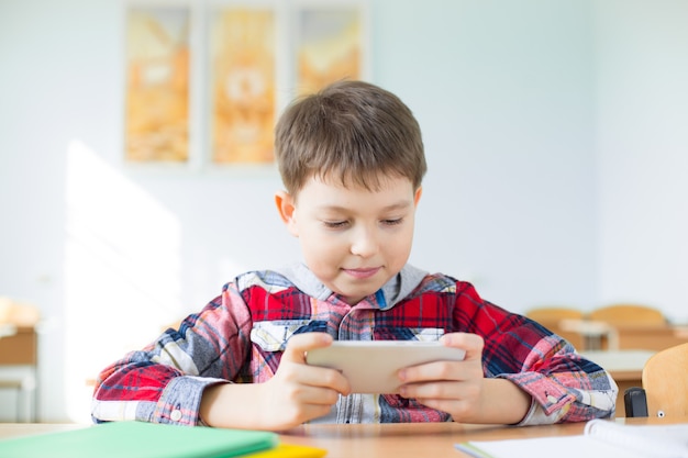 Menino brincando com smartphone na escola