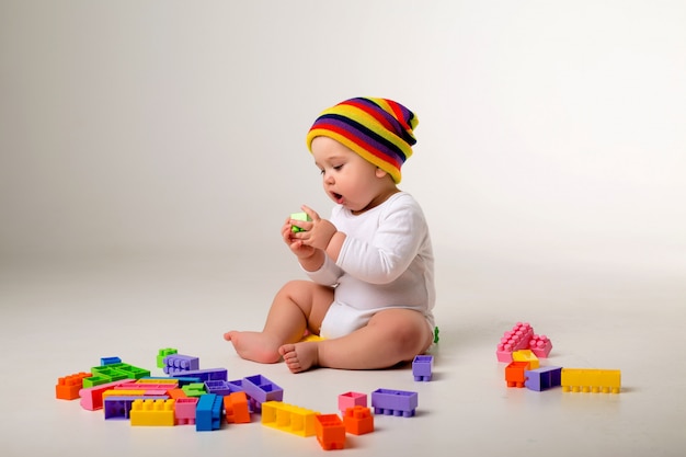 menino brincando com um construtor multicolorido em uma parede branca