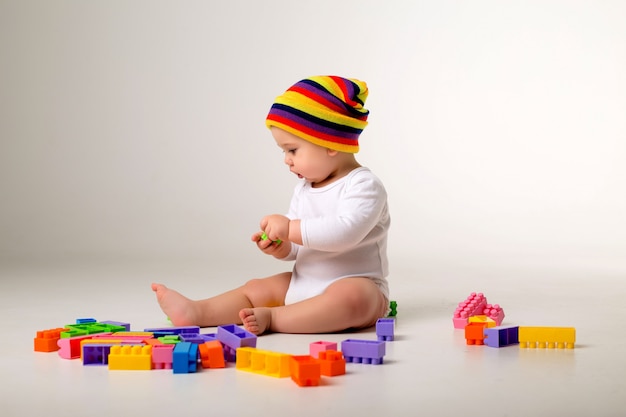 menino brincando com um construtor multicolorido em uma parede branca