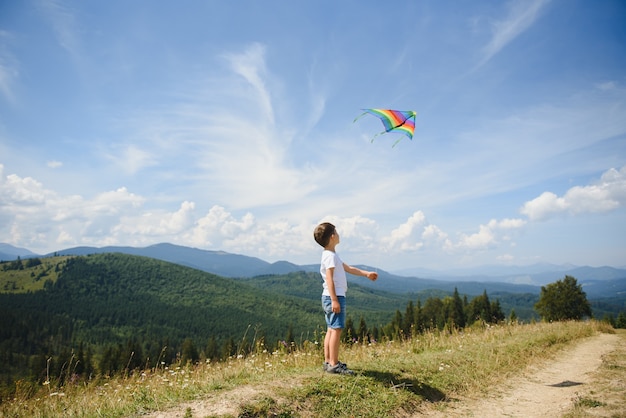 Menino brincando com uma pipa nas montanhas