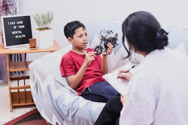 menino brincando de brinquedo de motocicleta enquanto contava a história para uma psicóloga profissional