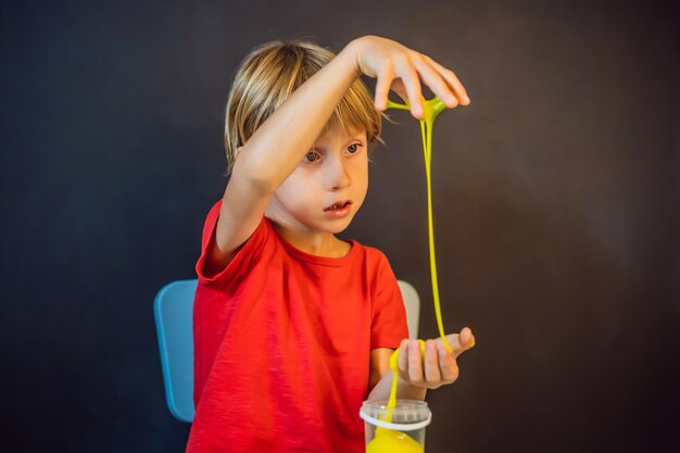 Menino brincando de brinquedo feito à mão chamado slime brincadeira de criança com slime kid squeeze e alongamento de slime