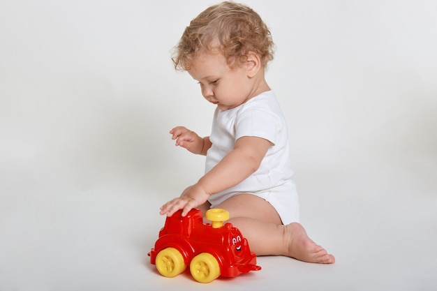 Menino brincando de carro isolado no branco